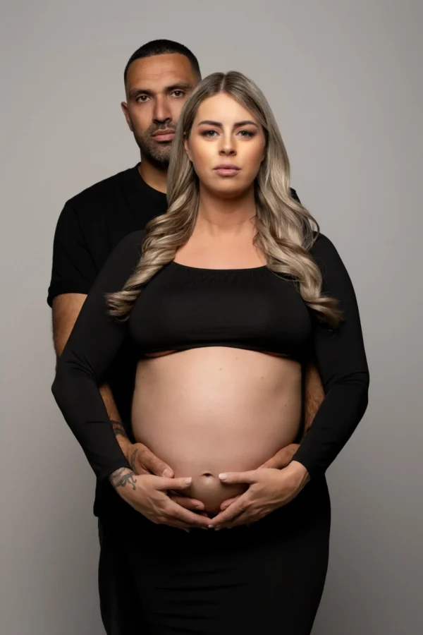 Klassieke zwangerschapsfoto met partner in warme studio-opstelling